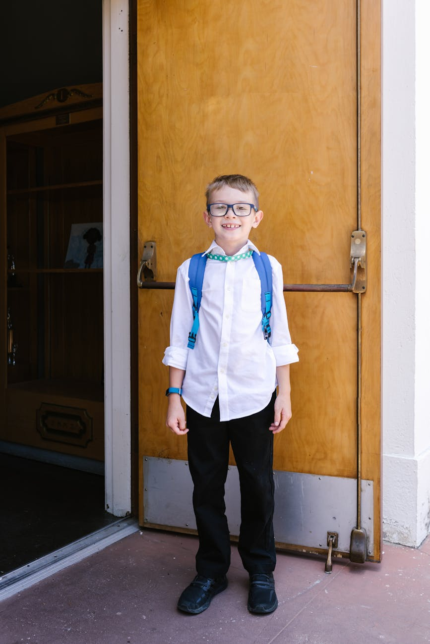 a student in blue backpack standing near the wooden door